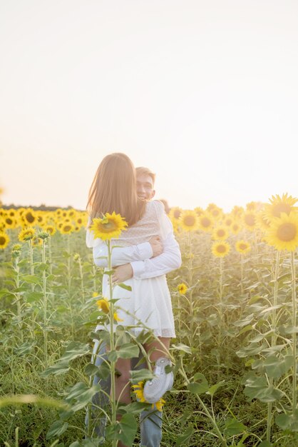 Natureza do outono. Jovem casal romântico caminhando em um campo de girassol ao pôr do sol