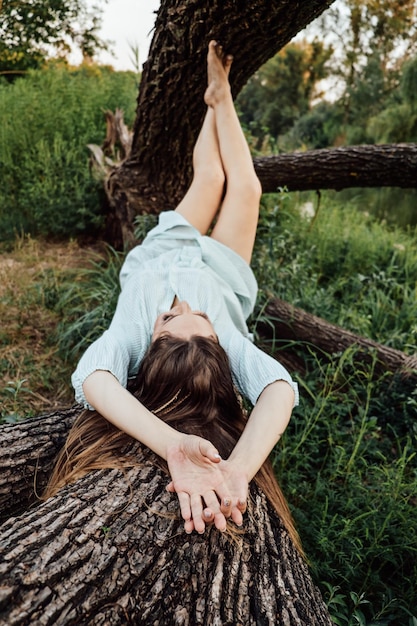Natureza e saúde mental mulher descalça em um vestido está descansando perto das árvores na natureza