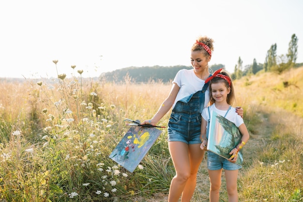 Natureza ensolarada, mãe e filha pintam um quadro em um parque, pintando uma criança, criatividade infantil.