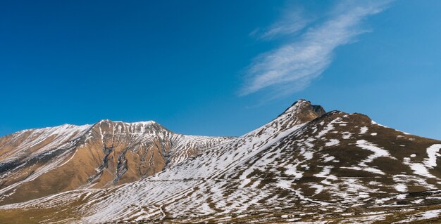 Natureza mágica e encantadora, encostas de altas montanhas cobertas de neve branca, sob um céu azul