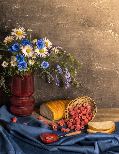 Foto natureza morta clássica com colheita de verão framboesa, pão e flores