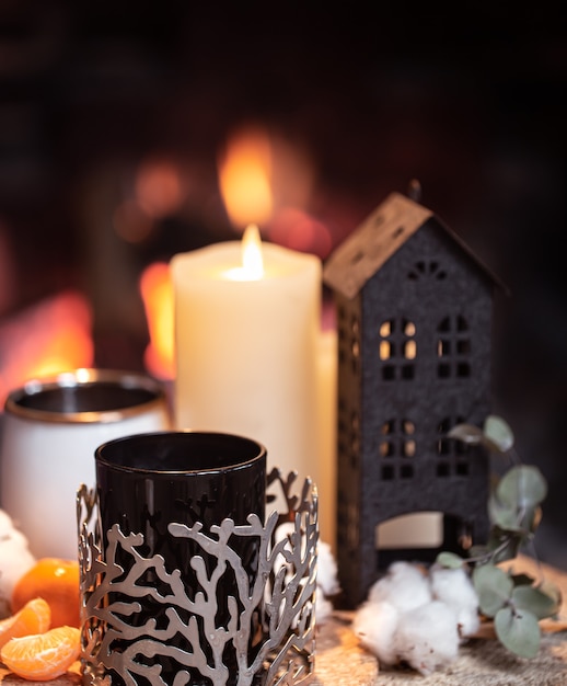 Natureza morta com bebidas quentes, velas e decoração no contexto de uma lareira.