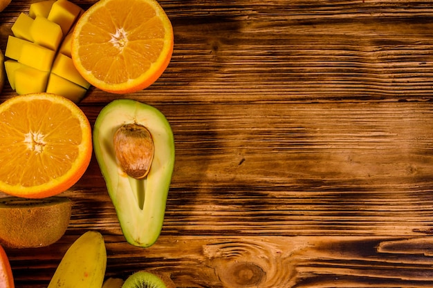 Natureza morta com frutas exóticas. Bananas, manga, laranja, abacate, toranja e kiwis na mesa de madeira rústica. Vista do topo