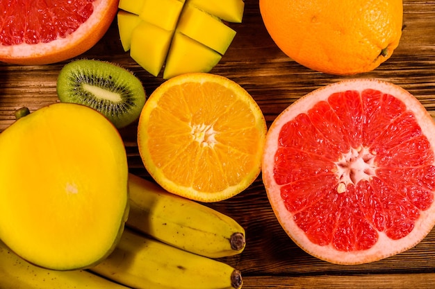 Natureza morta com frutas exóticas bananas manga laranjas toranja e kiwis na mesa de madeira vista superior