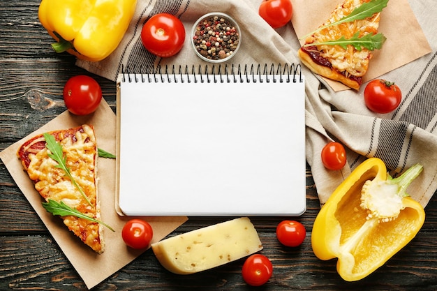 Foto natureza morta com ingredientes para pizza e caderno de receitas na mesa de madeira