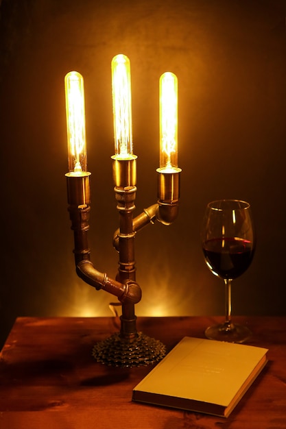 Natureza morta com lâmpada elétrica artesanal, livro e taça de vinho
