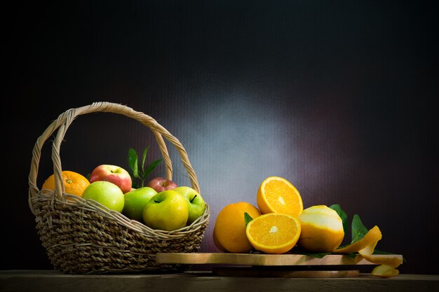 Natureza morta com laranjas e maçãs em uma mesa de madeira.