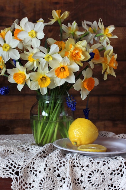 Natureza morta com narcisos amarelos e limão sobre uma mesa