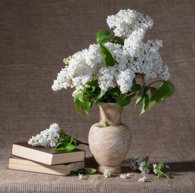 Natureza morta com ramos floridos de lilás em vasos e livros