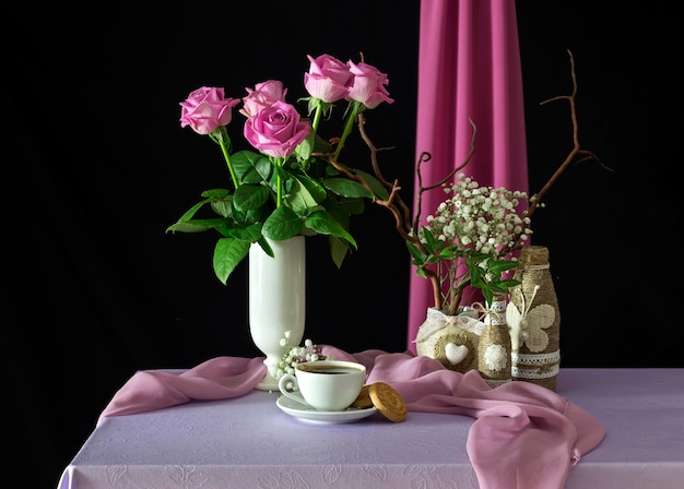 Natureza morta com rosas cor de rosa e café em uma xícara branca em uma mesa fechada