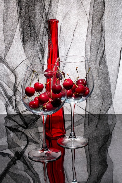 Natureza morta com uma garrafa vermelha e cerejas em copos