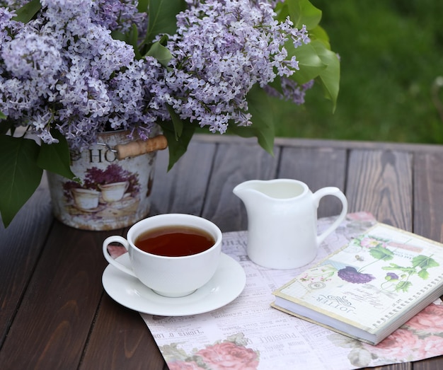 natureza morta com uma xícara de chá matinal e flores lilás