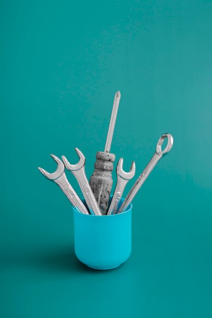 Natureza morta criativa em estilo minimalista, vaso com ferramentas de trabalho: chave de fenda, chaves em um fundo colorido. Cartão de saudação de conceito