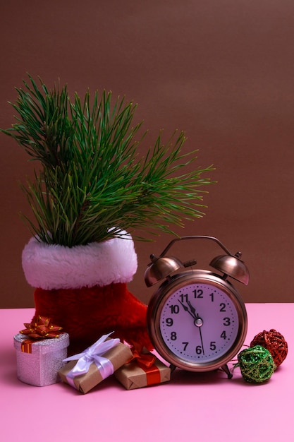 Natureza morta de ano novo com presentes, enfeites de Natal e um despertador em um fundo colorido. Feche com espaço de cópia. Foto vertical