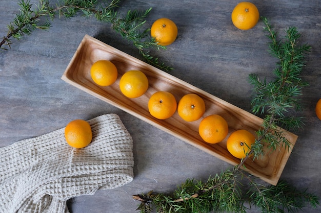 Natureza morta de Natal ou Ano Novo de tangerinas em uma placa retangular de madeira com ramos de abeto