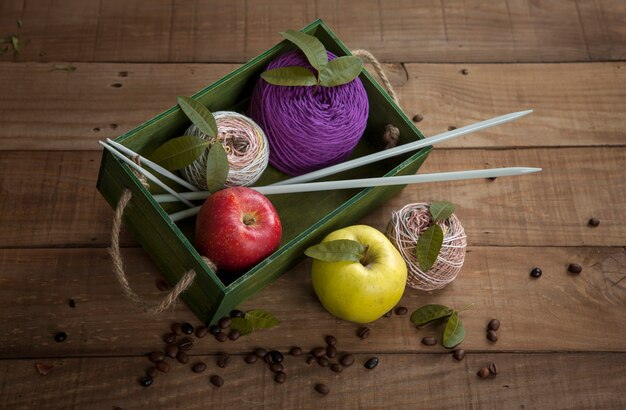 Foto natureza morta de novelos de lã, agulhas de tricô e frutas