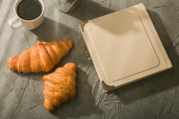 Natureza morta para uma agradável xícara turca de café da manhã e croissants com livro sobre o conceito de pausa para o almoço na mesa