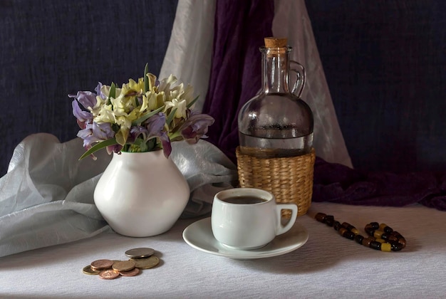 Natureza morta Íris selvagens em um vaso e uma xícara branca de café em uma mesa fechada