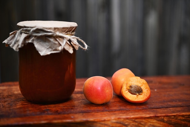 Natureza morta Um pote de geléia de damasco caseiro damascos maduros prontos para comer em uma superfície de madeira rústica Conceito de conservas