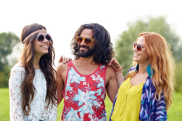 natureza, verão, cultura jovem e conceito de pessoas - sorrindo jovens amigos hippies em óculos de sol falando ao ar livre