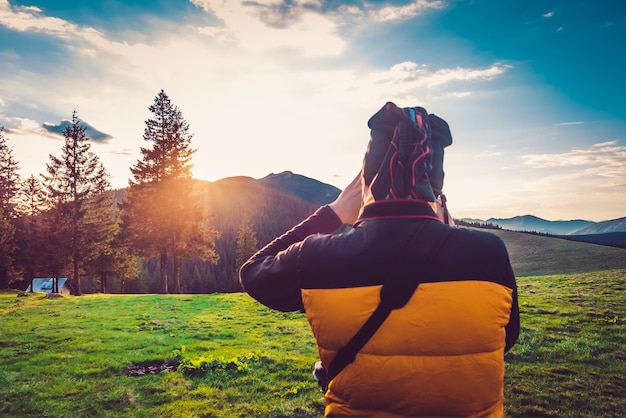 Naturfotograf Tourist mit Kamera, die ein Foto in der verträumten Sonnenuntergangslandschaft der Berge macht