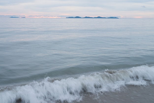 Foto naturhintergrund der küstenstrandwelle und -küste, klarer blauer himmel mit wolke und sonnenlichtwasseroberfläche für urlaubsentspannungs-lebensstillandschaftskonzept