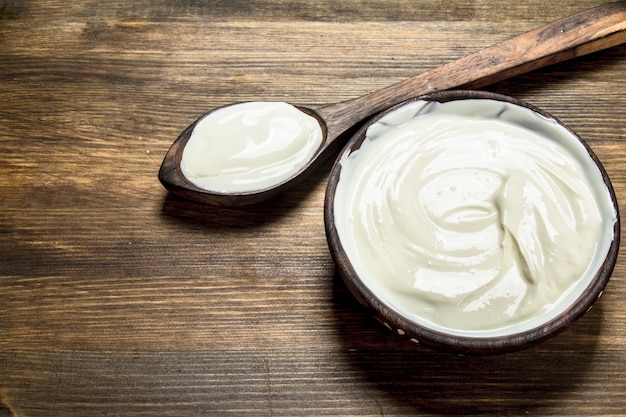 Naturjoghurt in einer Schüssel mit einem Löffel auf einem Holztisch