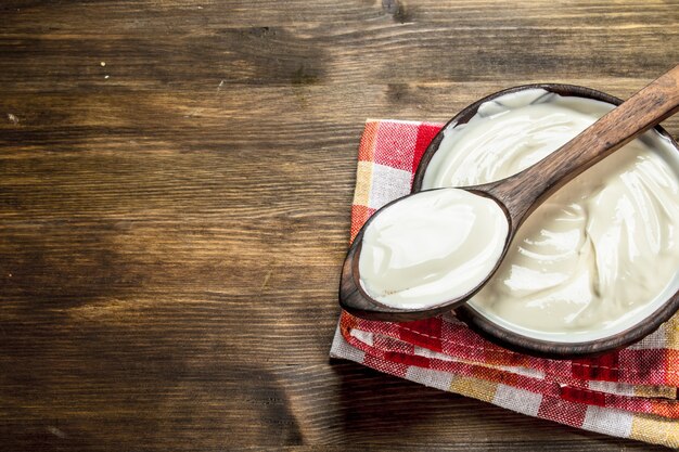 Naturjoghurt in einer Schüssel mit einem Löffel auf einem Holztisch