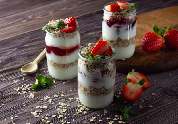 Naturjoghurt mit Marmelade, Müsli und frischen Erdbeeren, Minzblättern. Gesundes Frühstückskonzept.