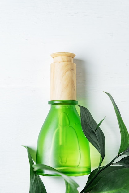 Naturkosmetik-Hautpflegeflasche mit Pipette und organischem grünem Blatt auf weißem Hintergrund. Hausgemachtes Heilmittel- und Schönheitsproduktkonzept.