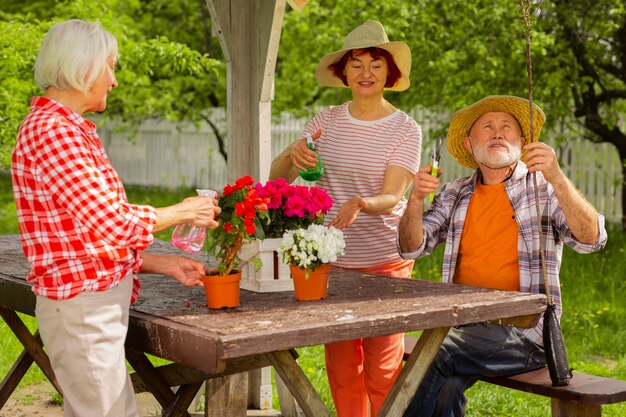 Naturliebhaber. Rentner und zwei Frauen, die sich um Blumen kümmern, sitzen zusammen