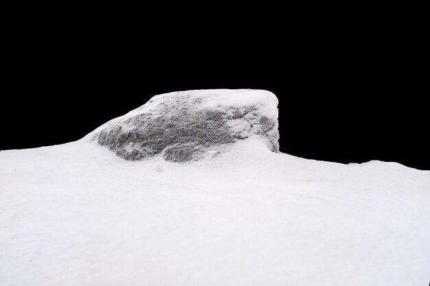 Naturstein im Schnee isoliert auf schwarzem Hintergrund Foto in hoher Qualität