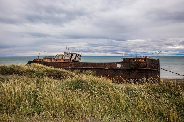 Un naufragio se sienta en las dunas de arena de la playa.