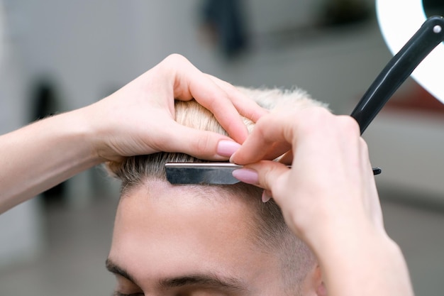 Navalha. processo de corte de cabelo de jovem loiro em salão de barbearia, conceito de barbearia para homens e meninos
