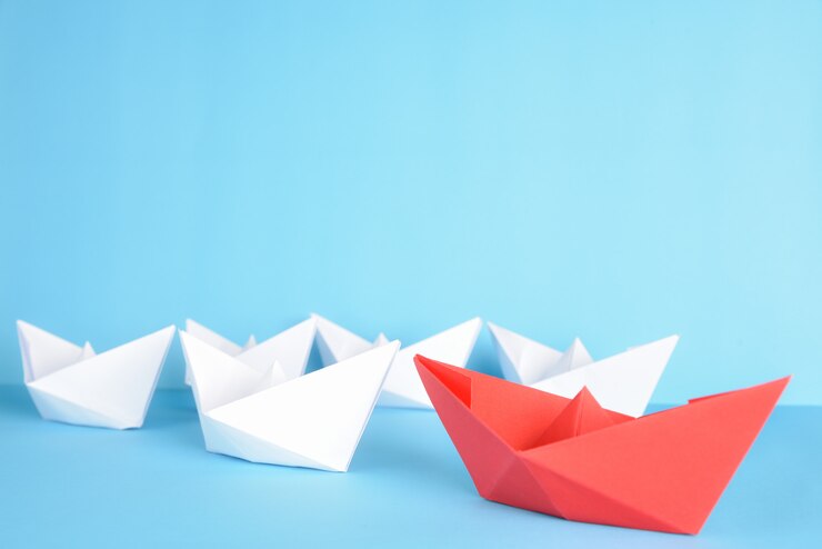La nave de papel roja lleva entre blanco sobre azul. Concepto de liderazgo.