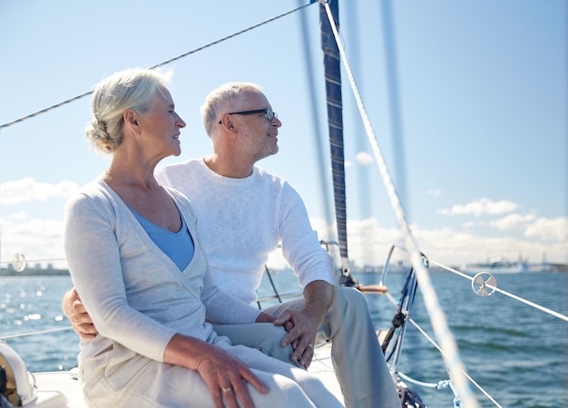 navegación, edad, turismo, viajes y concepto de personas - feliz pareja mayor abrazándose en velero o cubierta de yates flotando en el mar