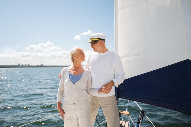 navegación, edad, turismo, viajes y concepto de personas - feliz pareja mayor abrazándose en velero o cubierta de yates flotando en el mar