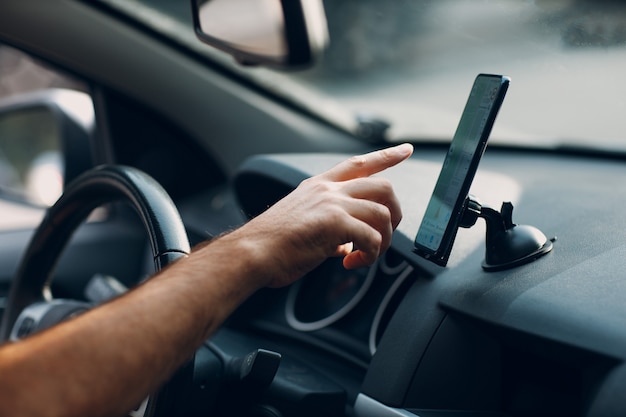 Navegador en el transporte de vehículos automóviles de cercanías. Conductor, hombre, señalar con la mano, dedo, teléfono móvil, navegador, aplicación, mientras, conducción, coche.