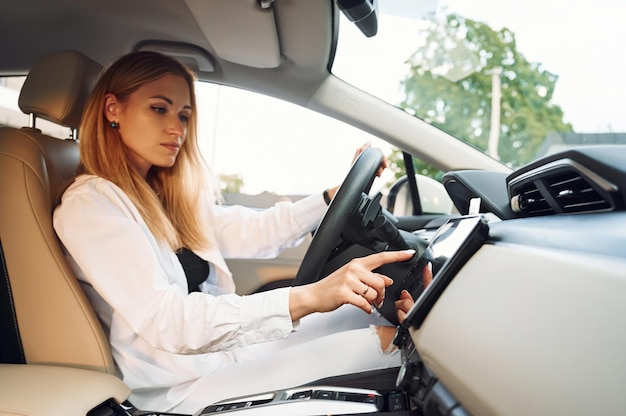 Navegando na interface do veículo Jovem com roupas brancas está com seu carro elétrico durante o dia