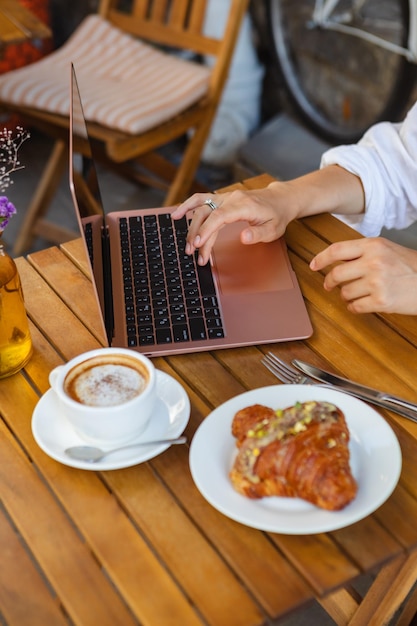 Navegar por Internet en un café de verano con un croissant