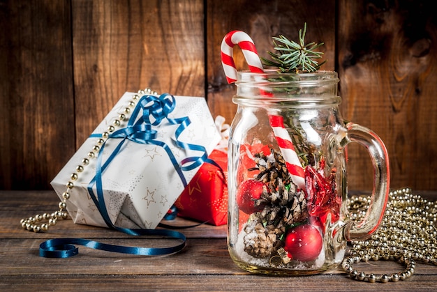 Navidad, año nuevo concepto. Mason Jar con adornos navideños, conos de abeto, nieve artificial, bastón de caramelo y rama de abeto.