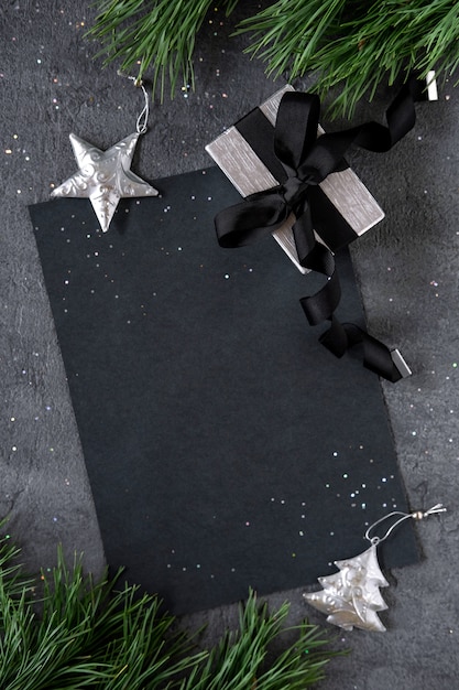 Navidad, año nuevo fondo negro elegante y en blanco con una rama de abeto, regalo con adornos de estrellas plateadas. Copie el espacio. Vista superior