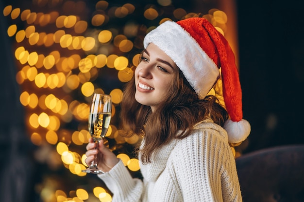 Navidad, año nuevo. Mujer bonita en suéter caliente sentado en la silla con champán