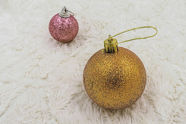 Navidad bolas naranjas y rosas brillantes sobre fondo de piel blanca.