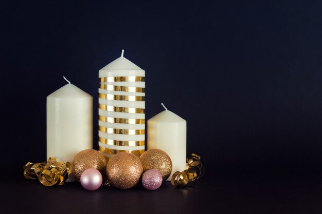 Navidad, composición de año nuevo con velas blancas, adornos dorados, bolas sobre fondo negro. Foto con copia espacio en blanco.