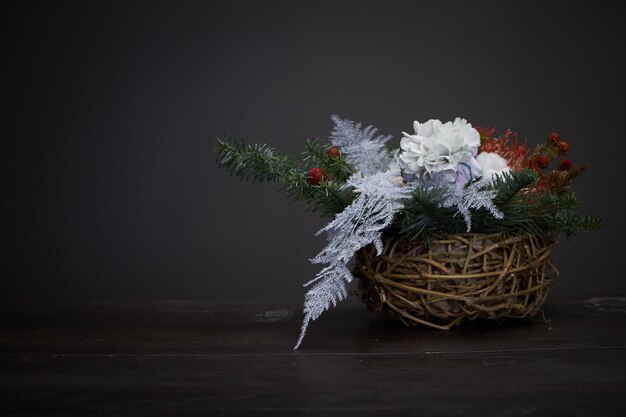 Navidad y composición. Cesta de mimbre con ramas de abeto decoradas con materiales naturales sobre fondo oscuro.