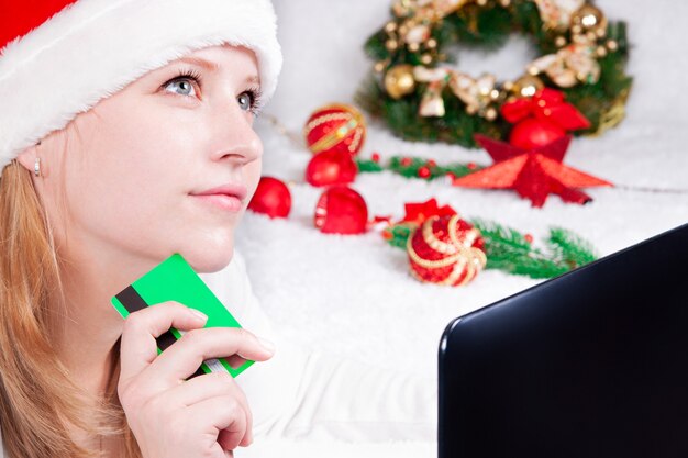 Navidad compras en línea trabajo y educación Mujer con portátil en casa en Santa hat ventas de vacaciones de invierno