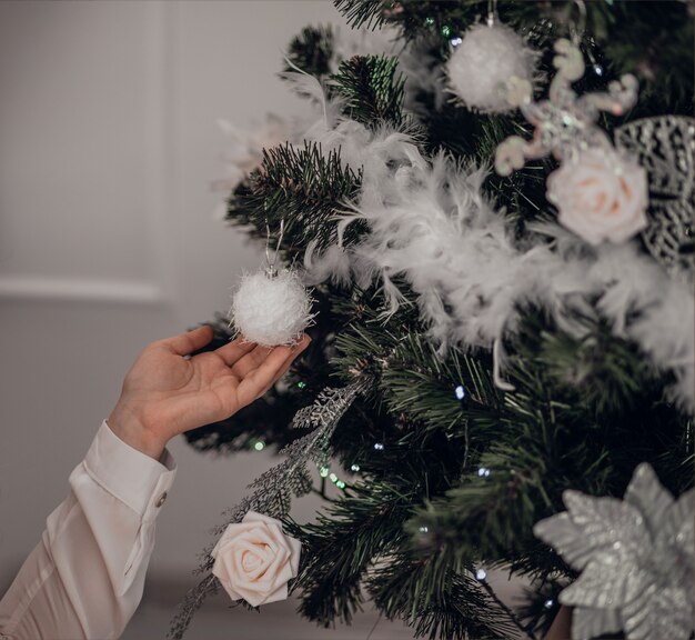 Navidad. Dama elegante junto al árbol de Navidad sosteniendo una bola de Navidad