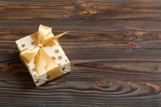 Navidad envuelta u otro regalo hecho a mano de vacaciones en papel blanco con cinta dorada sobre fondo de color Presente la decoración de la caja de regalo en la vista superior de la mesa de color con espacio de copia