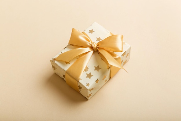 Navidad envuelta u otro regalo hecho a mano de vacaciones en papel blanco con cinta dorada sobre fondo de color Presente la decoración de la caja de regalo en la vista superior de la mesa de color con espacio de copia